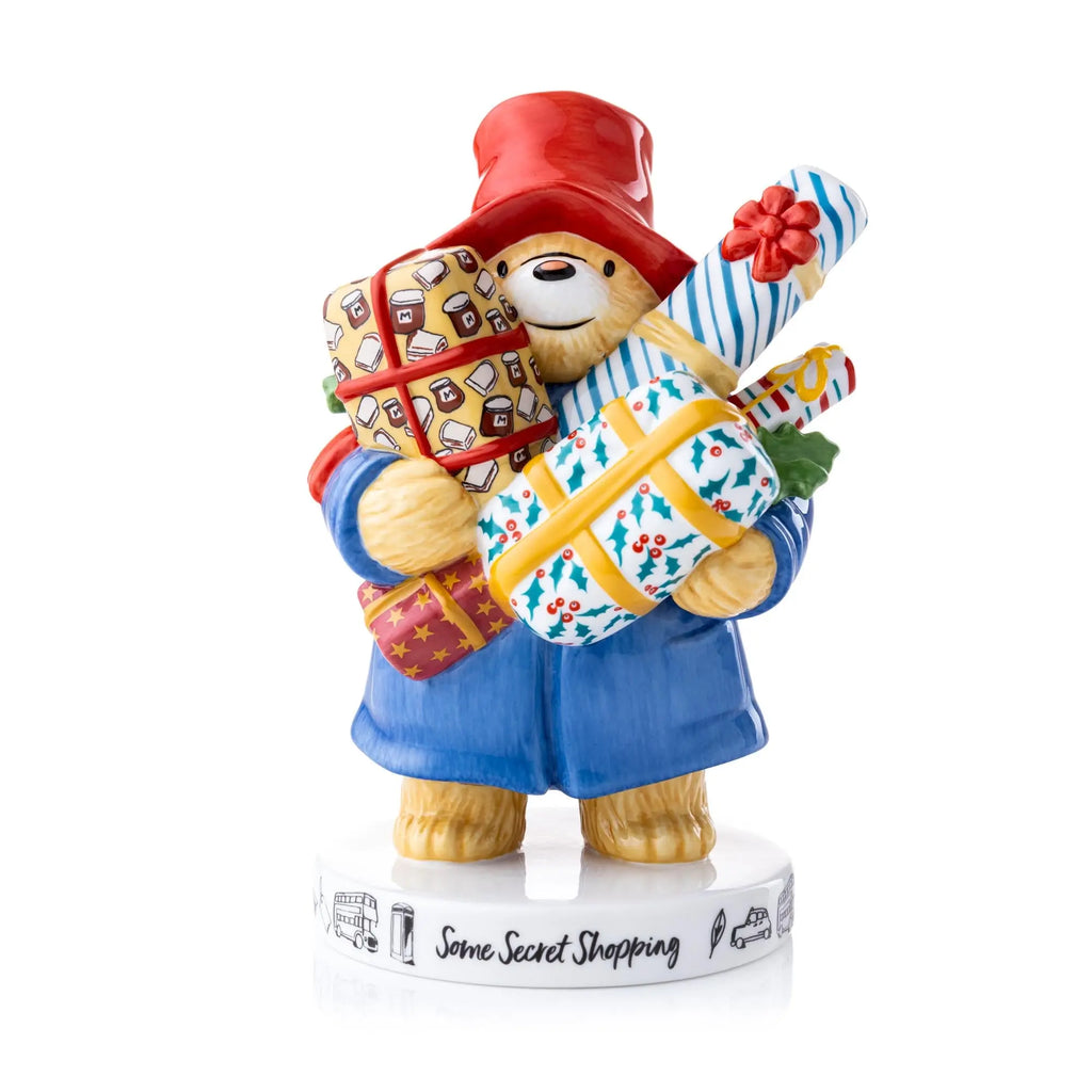 Fine bone china figurine: bear in blue coat and red hat holding striped shopping bag.