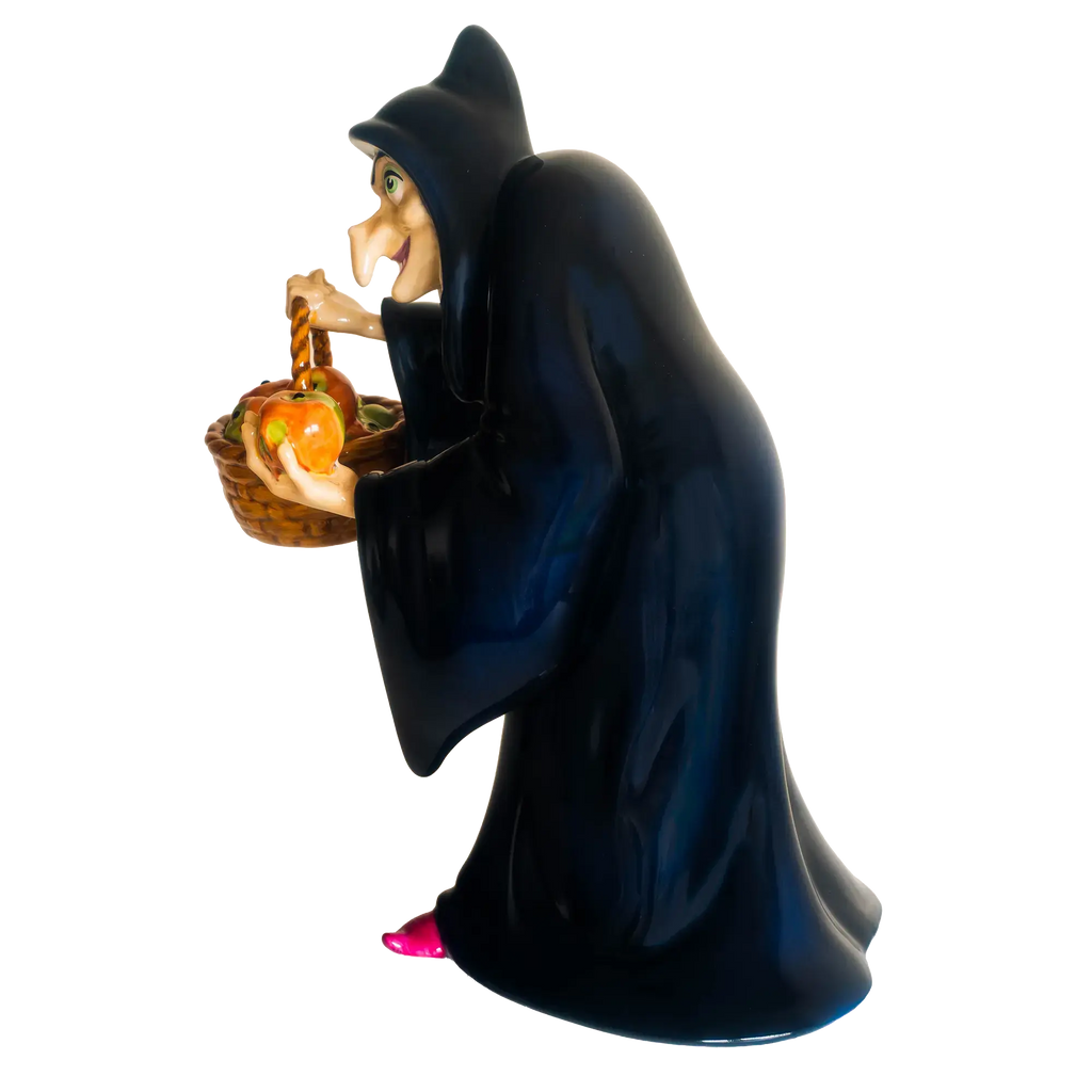 Side view witch figurine holding a basket of glowing apples, long dark blue robe