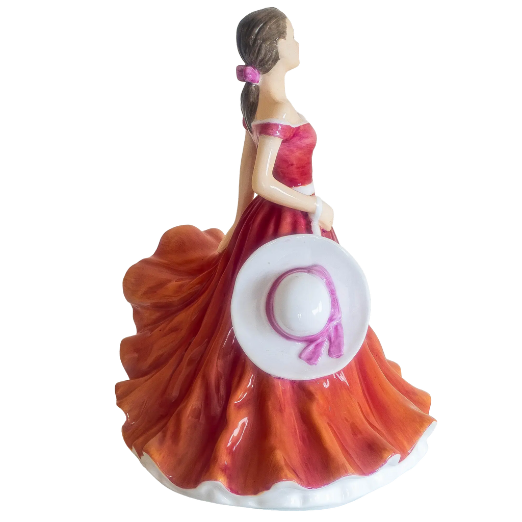Bone china figurine woman in red dress with orange skirt and a white and purple decorative plate