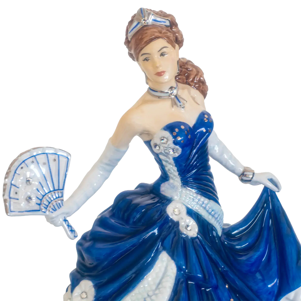 Porcelain lady figurine in blue gown with white gloves holding a fan