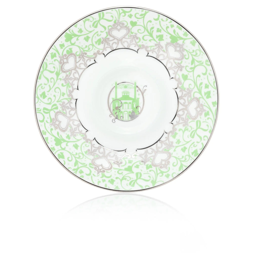 Matching saucer with green floral pattern and ornate heart motif on white porcelain